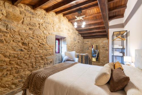 a bedroom with a large bed in a stone wall at Vagalume in Vedra