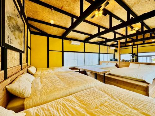 two beds in a room with yellow walls at 風乃釣り宿 in Shirahama