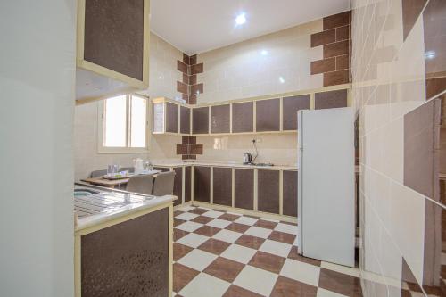 a kitchen with a refrigerator and a checkered floor at صدي للشقق المخدومة in Khamis Mushayt