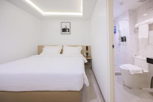a bedroom with a white bed and a bathroom at Global Hotel Pratunam Bangkok in Bangkok