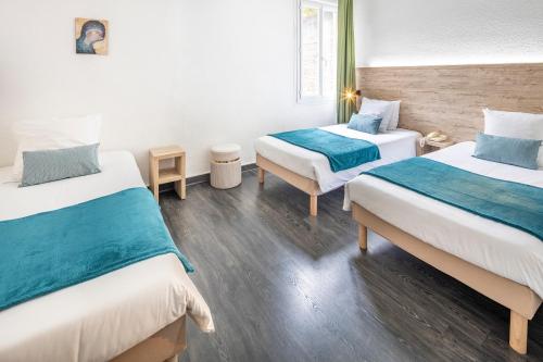 a hotel room with two beds with blue sheets at Hôtel Estival Arriel entièrement climatisé in Lourdes