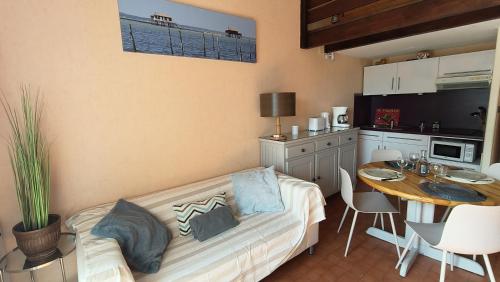 a living room with a couch and a kitchen with a table at Appartement du Port Neuf in Lanton