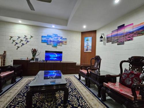 a living room with chairs and a tv and a table at Villa Sapphire by Blue Robin - Private Taiping Villa 20pax River & Waterfall in Taiping