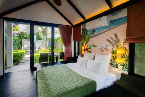 a bedroom with a bed with a green bedspread at Tolani Resort Koh Samui in Lamai