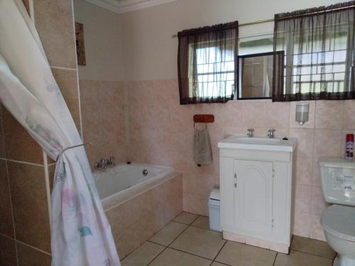 a bathroom with a tub and a toilet and a sink at Petronella Guest House in Bethlehem