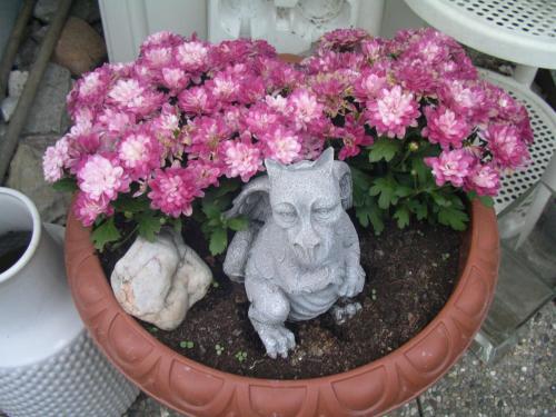 a pot of pink flowers with a statue in it at B&B Zur Tanne in Bad Dürrheim