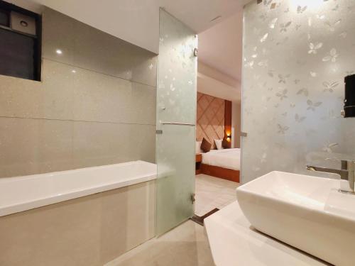 a bathroom with a shower and a sink and a tub at Hotel Sterling Executive in Navi Mumbai