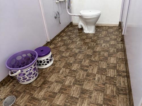a bathroom with a toilet and two buckets on the floor at Vintage Vista Camps in Kasol