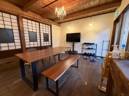 a dining room with a wooden table and a tv at GLOCE西会津 ふくの屋 l 古きを知り新しきを愉しむ l 築110年超の古民家が綴る心地よい宿 in Yanaizu