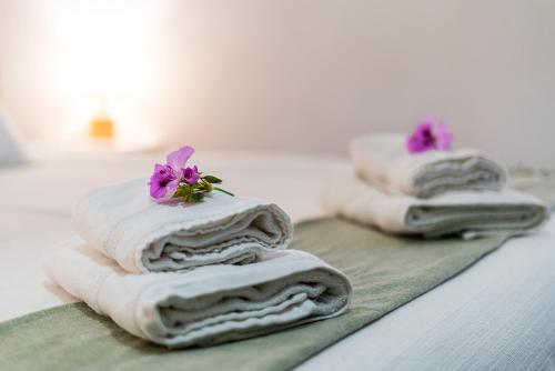 three towels with flowers on top of them on a counter at Vivenda Aromas do Algarve in Monte Raposo