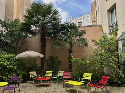 a patio with colorful chairs and tables and a palm tree at Hôbou - ex Hotel Acanthe in Boulogne-Billancourt