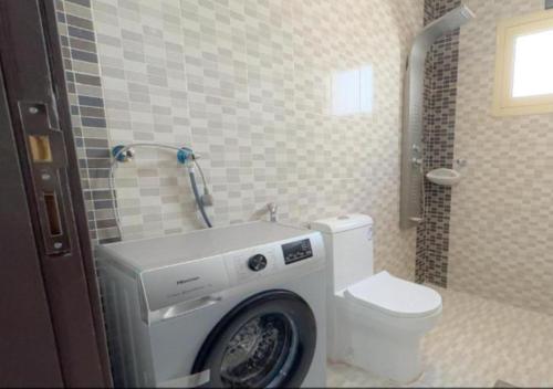 a bathroom with a washing machine next to a toilet at شقق سكنية بالخالدية in Al ‘Awālī