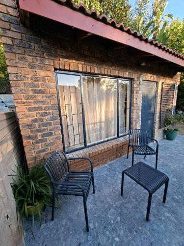 two chairs and a table in front of a brick building at De Windmolen in Centurion