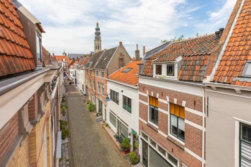 an alley in the city with buildings and a clock tower at Het Herenhuis Middelburg in Middelburg