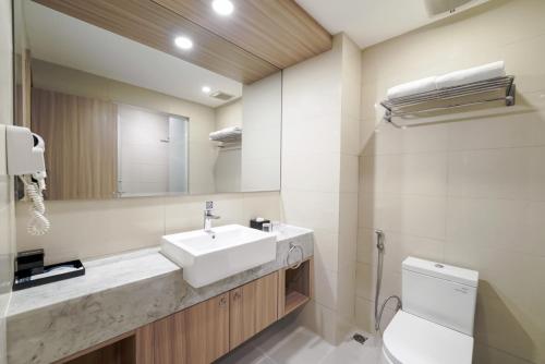 a bathroom with a sink and a toilet and a mirror at Aston Kemayoran City Hotel in Jakarta