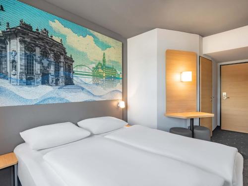 a bedroom with a white bed and a painting on the wall at B&B HOTEL Saarbrücken-Ost in Saarbrücken