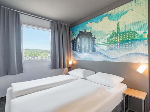 a bedroom with two beds and a painting on the wall at B&B HOTEL Saarbrücken-Ost in Saarbrücken
