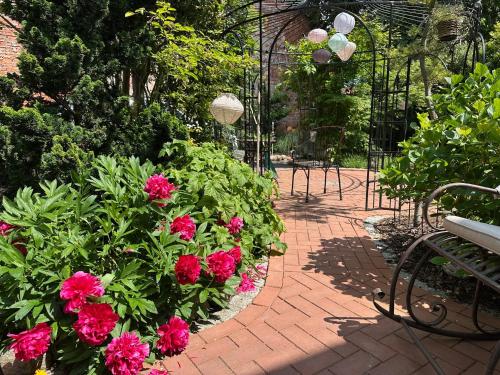 a garden with pink flowers and a park bench at RitterLiving Ferienapartment am Markt in Tangermünde