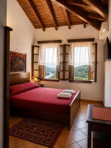 a bedroom with a red bed and two windows at Guva Mangalem Boutique Hotel & Restaurant -Berat Old Town View in Berat