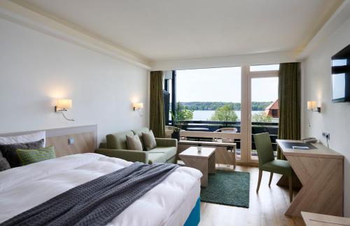ein Hotelzimmer mit einem großen Bett und einem Schreibtisch in der Unterkunft Hotel Schloss Berg in Berg am Starnberger See