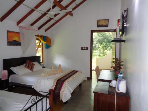 a bedroom with two beds and a desk and a window at Rimaka Village - Tourist Board Approved Hotel in Habarana