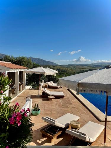 a patio with lounge chairs and a swimming pool at Vida Lenta Boutique Finca in Alora