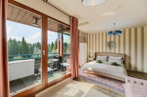 a bedroom with a bed and a balcony at Woodland Apartment in Silver Mountain Resort in Poiana Brasov