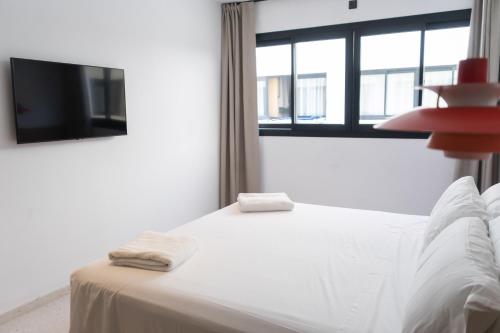 a bedroom with a bed with a tv and a window at The Boc Hostels - City in Palma de Mallorca