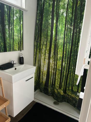 ein Badezimmer mit Fenster und einem Duschvorhang mit Waldmotiv in der Unterkunft Koziula - Domki i Leśne SPA na Kaszubach in Przywidz