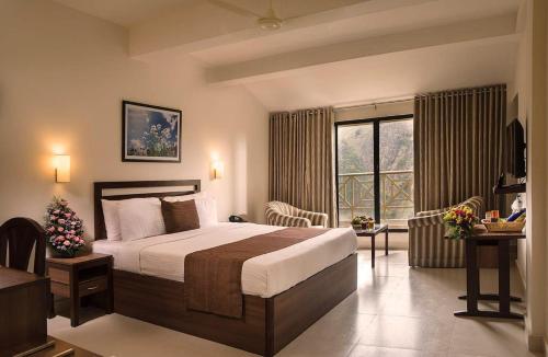 a bedroom with a large bed and a large window at Abad Copper Castle Resort in Munnar