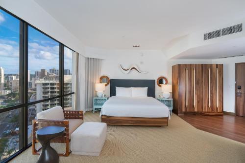 a bedroom with a king sized bed and large windows at Hyatt Centric Waikiki Beach in Honolulu