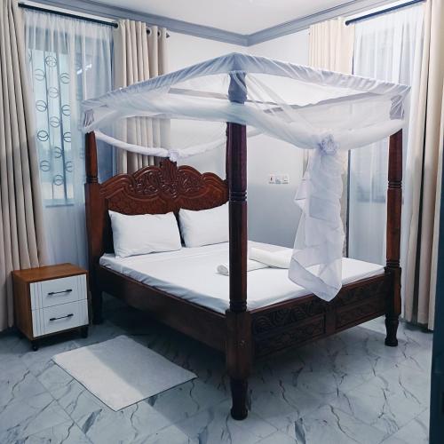 a bedroom with a canopy bed with white sheets at Summer Malindi Family House in Malindi