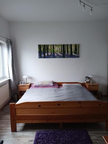 a bedroom with a wooden bed and a painting on the wall at Ferienwohnung Benzmann in Süderbrarup