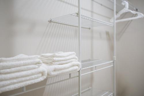 a towel rack with white towels on it in a bathroom at The Pier Beach Inn & Suites in Willemstad