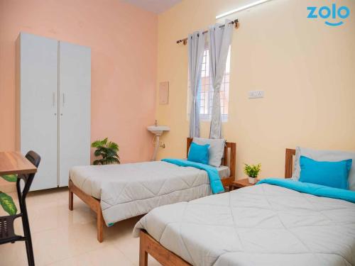 two beds in a room with blue pillows at Z Express Leela in Bangalore
