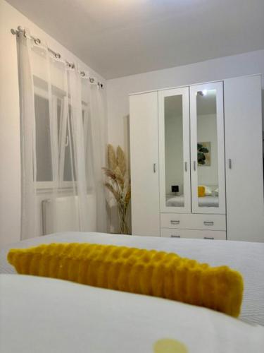 a white bedroom with a white bed with a yellow blanket at Rural Apartment Ante in Drniš
