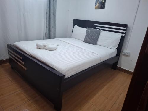 a bed with a black frame and white sheets at Bright Homes in Eldoret