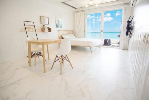 a white room with a desk and a table and a window at Taean Sharon Pension in Taean