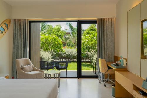 a hotel room with a bed and a desk and chairs at The Shore Trishvam in Pondicherry