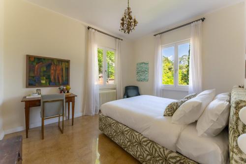 a bedroom with a bed and a desk and windows at La dolce riva - lake Cottage in Onno