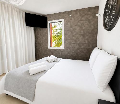 a bedroom with a large white bed and a clock on the wall at Élégante maison familiale, terrasse & piscine in Aigrefeuille-sur-Maine