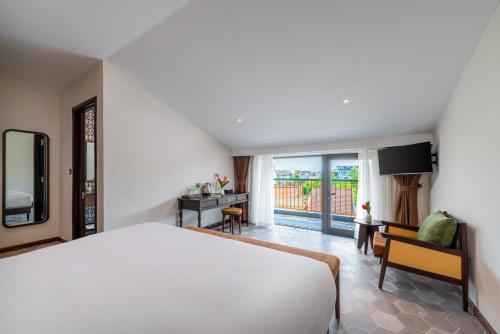 a bedroom with a bed and a desk and a balcony at BACKHOME BOUTIQUE Old Town Hoi An in Hoi An