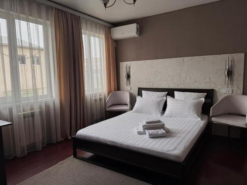 a bedroom with a bed with white sheets and pillows at Hotel Mansuri in Almaty