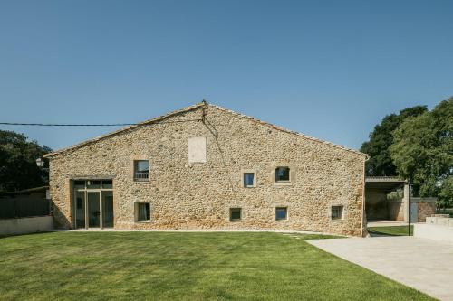 a large stone building with a grass yard at Casa Rural Mas Homs in Parets de Dalt