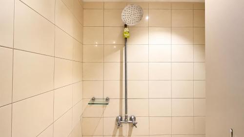 a white tiled shower with a shower head at Subwow Hostel in Bandung