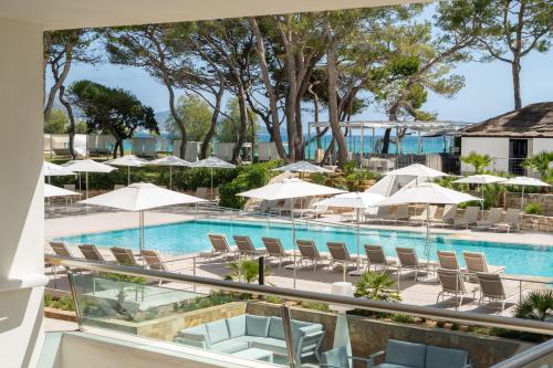 a view of a pool with chairs and umbrellas at Iberostar Selection Playa de Muro Village in Playa de Muro