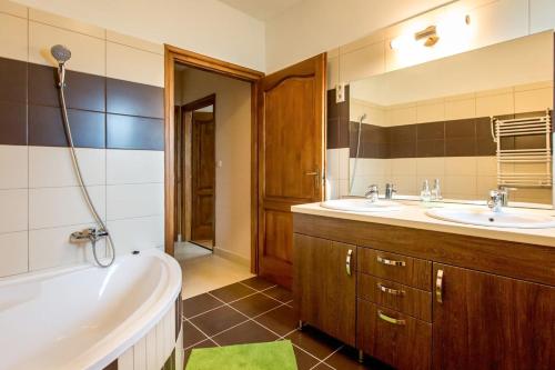 a bathroom with two sinks and a tub and a bath tub at Panoráma Vendégház Bükkösd in Bükkösd