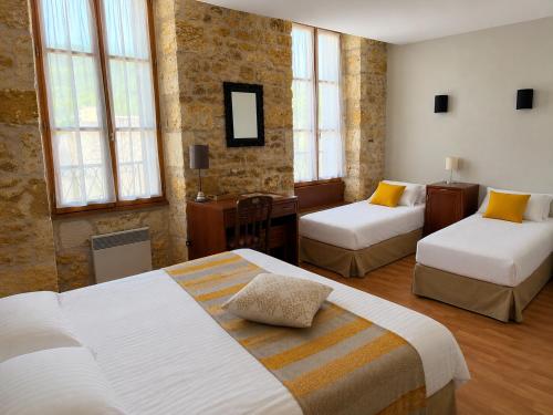 a hotel room with two beds and a desk at Hôtellerie de l'Abbaye Saint Amand in Saint-Amand-de-Coly