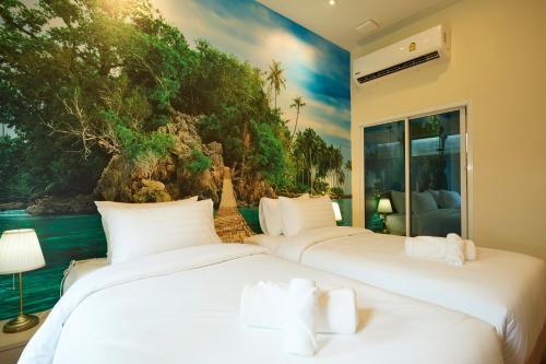 two beds in a room with a painting on the wall at Rocco Hotel Bangsaen in Ban Laem Thaen