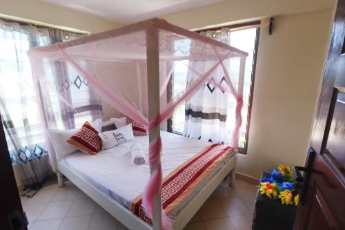 a bedroom with a bed with a canopy at The Nest Apartment Darad in Ukunda Airport